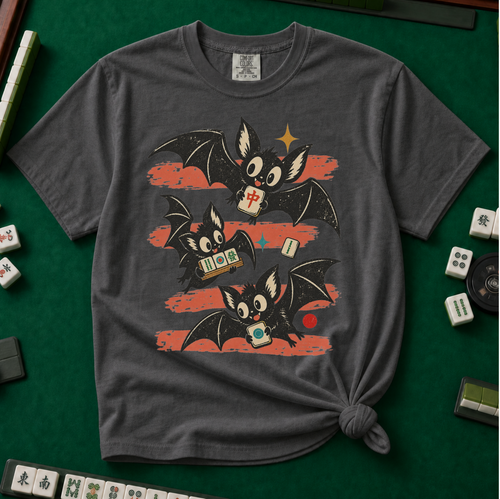 Bats Out Mahjong Shirt in Pepper - knotted tee on a light surface with mahjong tiles scattered around, printed with three mahjong tiles dressed as bats over the words Bats Out