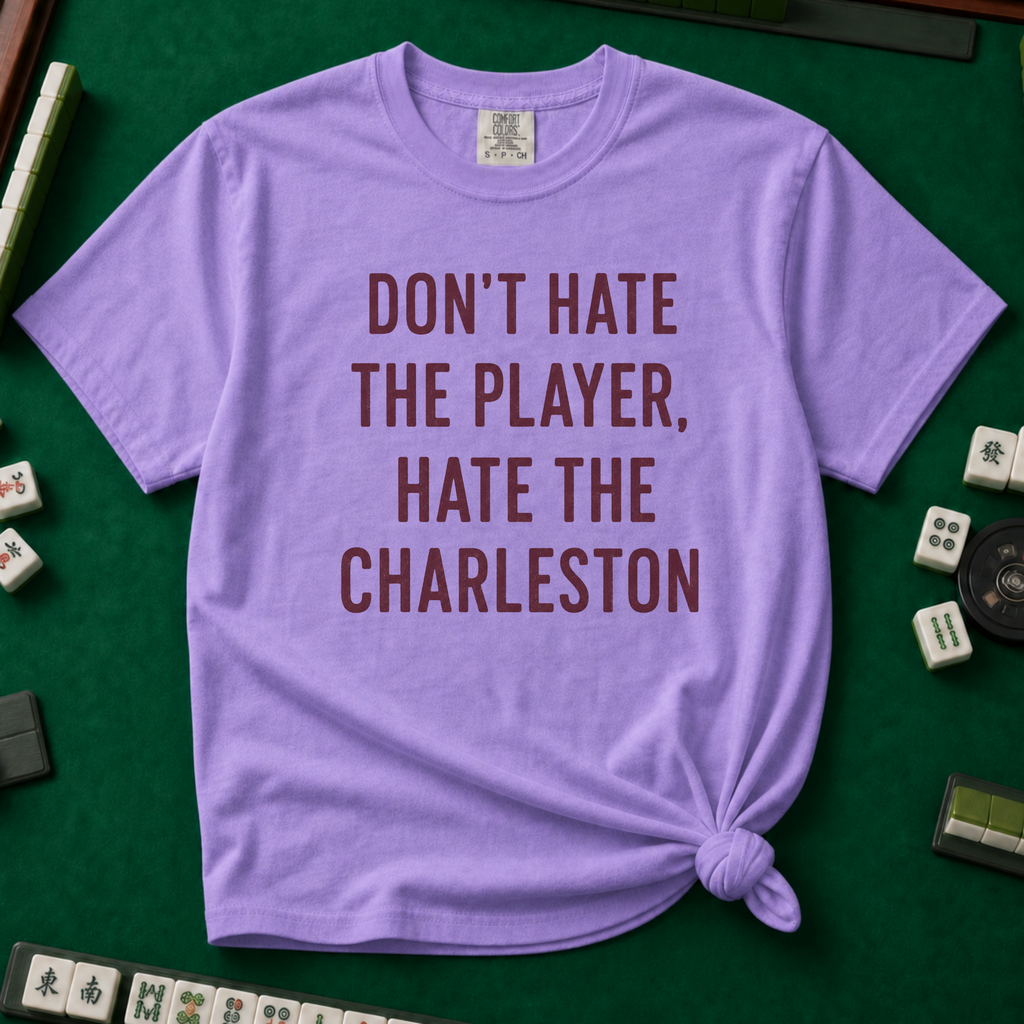 Don't Hate The Player Hate The Charleston T-Shirt in Violet, knotted flat lay on a green mahjong mat - "DON'T HATE THE PLAYER, HATE THE CHARLESTON" in deep burgundy block letters