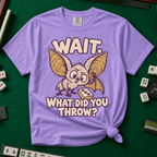 Wait What Did You Throw T-Shirt in Violet, knotted flat lay on a green mahjong mat - a wide-eyed fluffy bat with huge golden ears leaning in over a fallen dot tile - "WAIT. WHAT DID YOU THROW?" in cream bubble letters