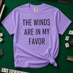 The Winds Are In My Favor T-Shirt in Violet, knotted flat lay on a green mahjong mat - "THE WINDS ARE IN MY FAVOR" in tall black letters