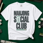 Mahjong Social Club Bold T-Shirt in White, knotted flat lay on a green mahjong mat - bold charcoal block letters "MAHJONG SOCIAL CLUB" with a green three-dot tile as the O in SOCIAL and a green pusher bar underline