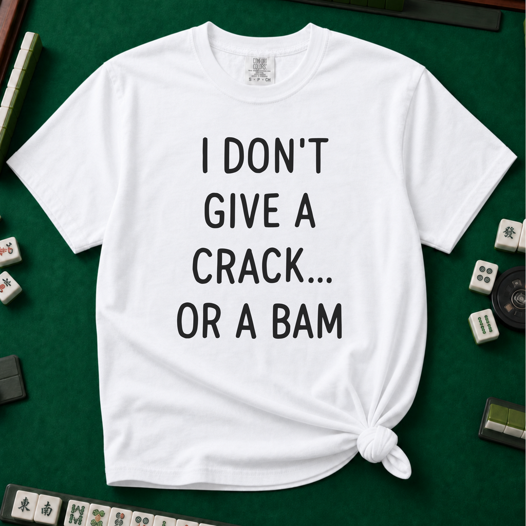 I Don't Give A Crack Or A Bam T-Shirt in White, knotted flat lay on a green mahjong mat - "I DON'T GIVE A CRACK... OR A BAM" in black handwritten-style letters