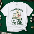 I Said Good Luck T-Shirt in White - knotted tee flat lay on a green mahjong mat with tiles, printed with a cream poodle in a pink scarf holding a teacup behind a rack of mahjong tiles, with the words I SAID GOOD LUCK. I MEANT TO ME.