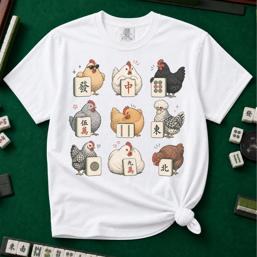 Mahjong Chickens T-Shirt in White, knotted flat lay on a green mahjong mat - a 3x3 grid of nine hens, each posing with a mahjong tile - a sunglasses hen with the green dragon, a white hen with the red dragon, a black hen with dots, a crested hen with East, and more
