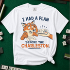 I Had A Plan Before The Charleston T-Shirt in White, knotted flat lay on a green mahjong mat - a stressed cartoon fox with glasses and a strategy sketch being handed three mahjong tiles, with the words "I HAD A PLAN BEFORE THE CHARLESTON."