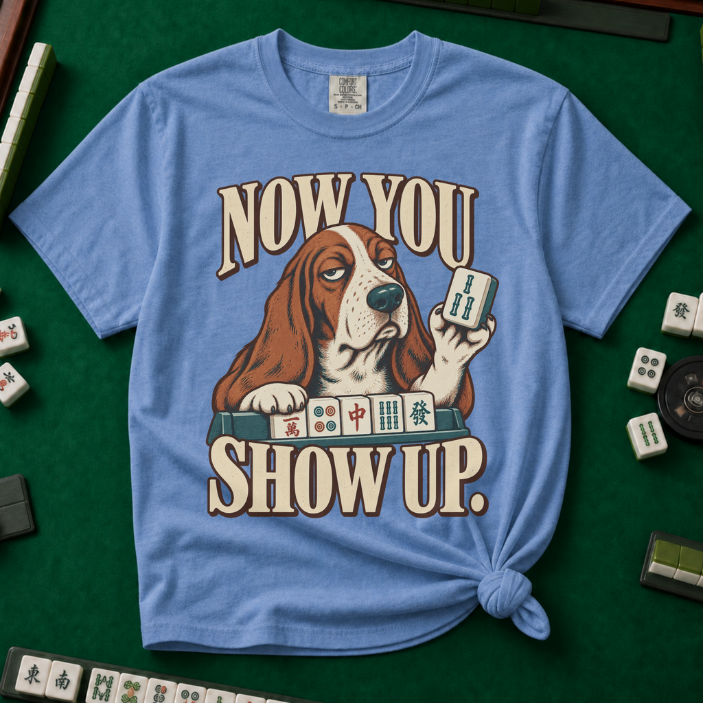 Now You Show Up Shirt in Blue Jean - knotted tee on a green mahjong mat with scattered tiles, printed with a basset hound peeking over a row of mahjong tiles and the words Now You Show Up