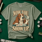 Now You Show Up Shirt in Moss - knotted tee on a green mahjong mat with scattered tiles, printed with a basset hound peeking over a row of mahjong tiles and the words Now You Show Up