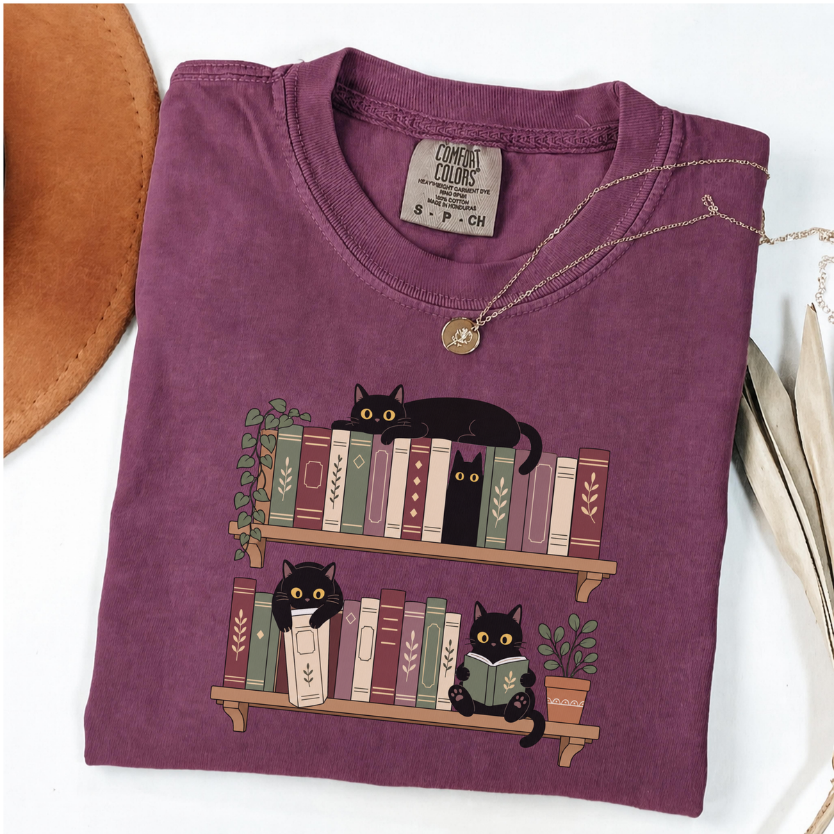 Berry Comfort Colors book-lover shirt featuring black cats among colourful bookshelves
