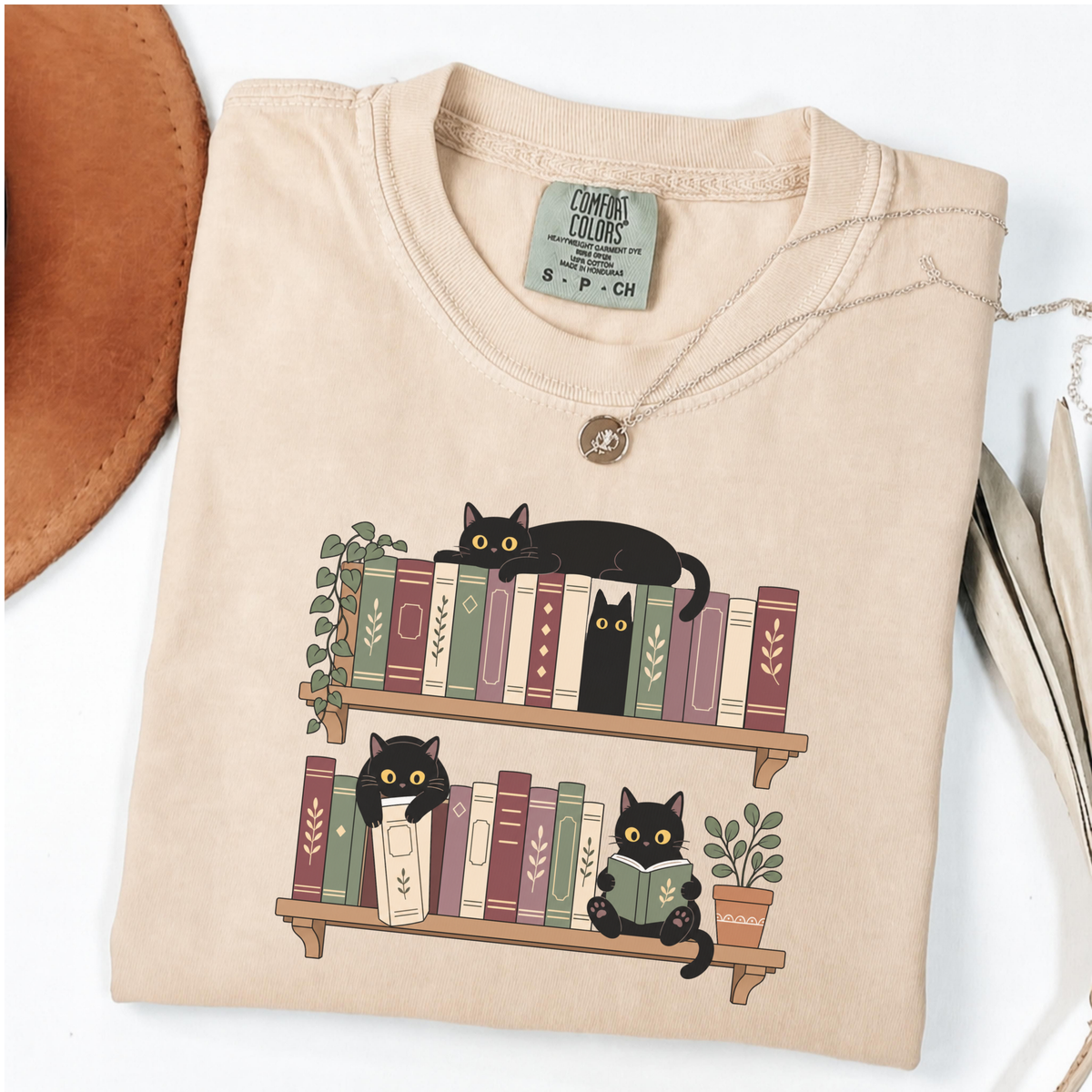 Ivory Comfort Colors book-lover shirt featuring black cats among colourful bookshelves
