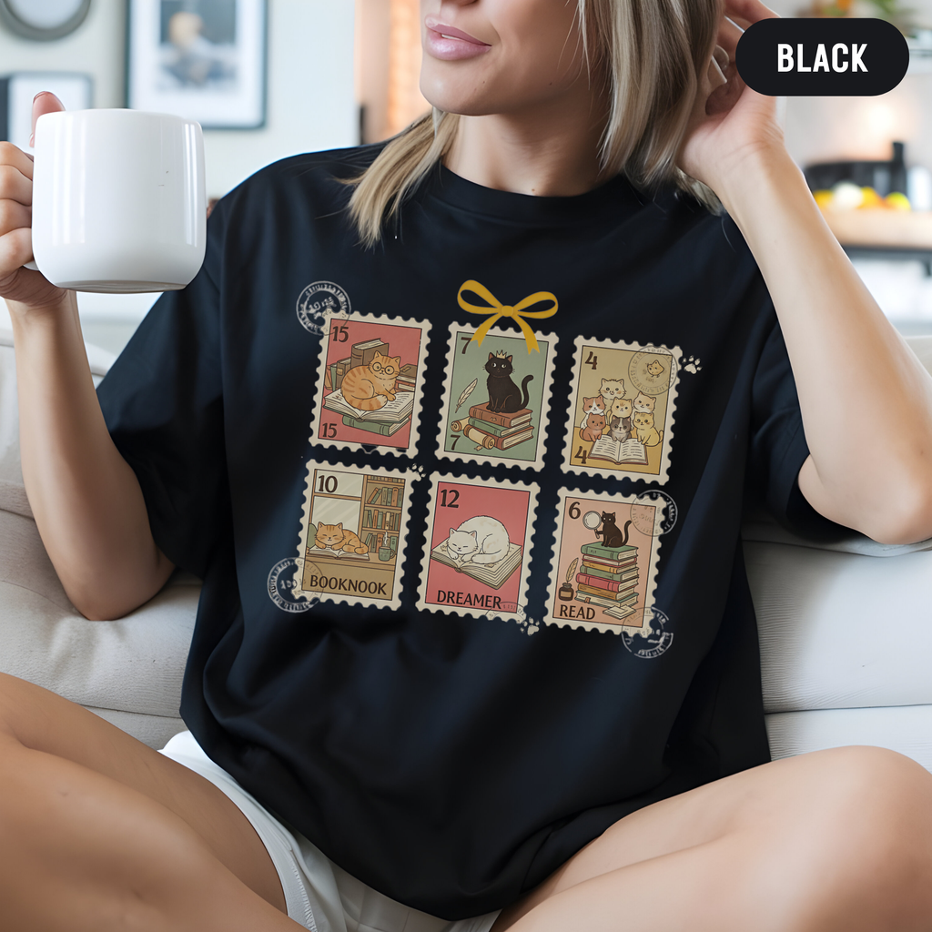 Model wearing a relaxed unisex Black  shirt featuring vintage postage-stamp cats with books.
