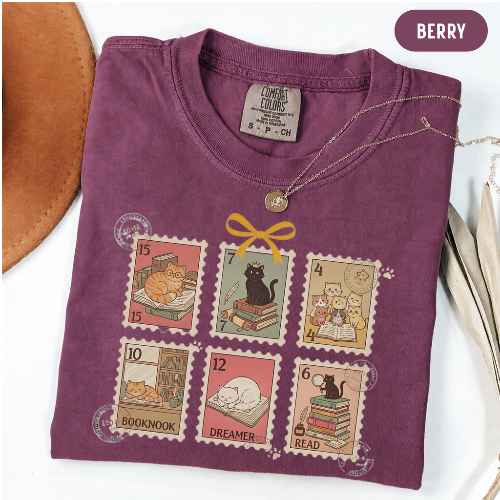 Berry shirt with six vintage-style postage stamps featuring cats reading and resting on books.