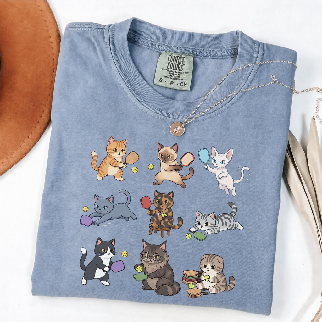 Blue Jean graphic T-shirt with nine cartoon cats playing pickleball