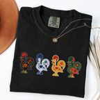 Black garment-dyed T-shirt featuring four colorful Portuguese folk-art roosters in a row
