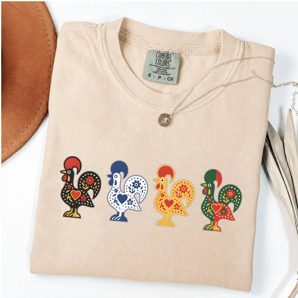 Ivory garment-dyed T-shirt featuring four colorful Portuguese folk-art roosters in a row