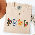 Ivory garment-dyed T-shirt featuring four colorful Portuguese folk-art roosters in a row