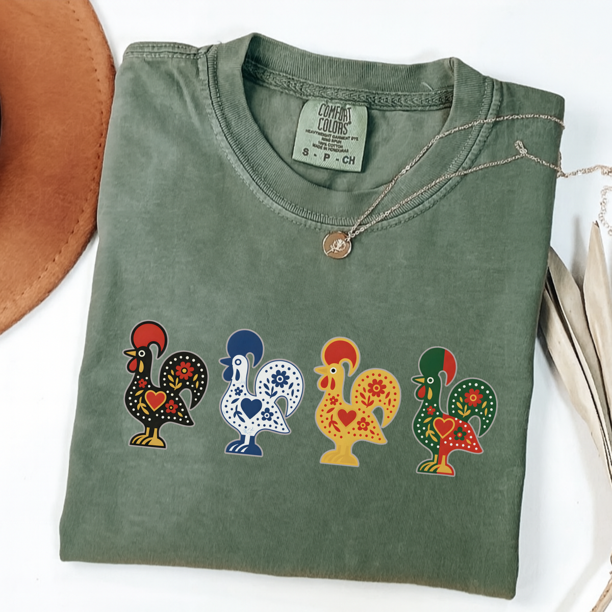 Moss garment-dyed T-shirt featuring four colorful Portuguese folk-art roosters in a row