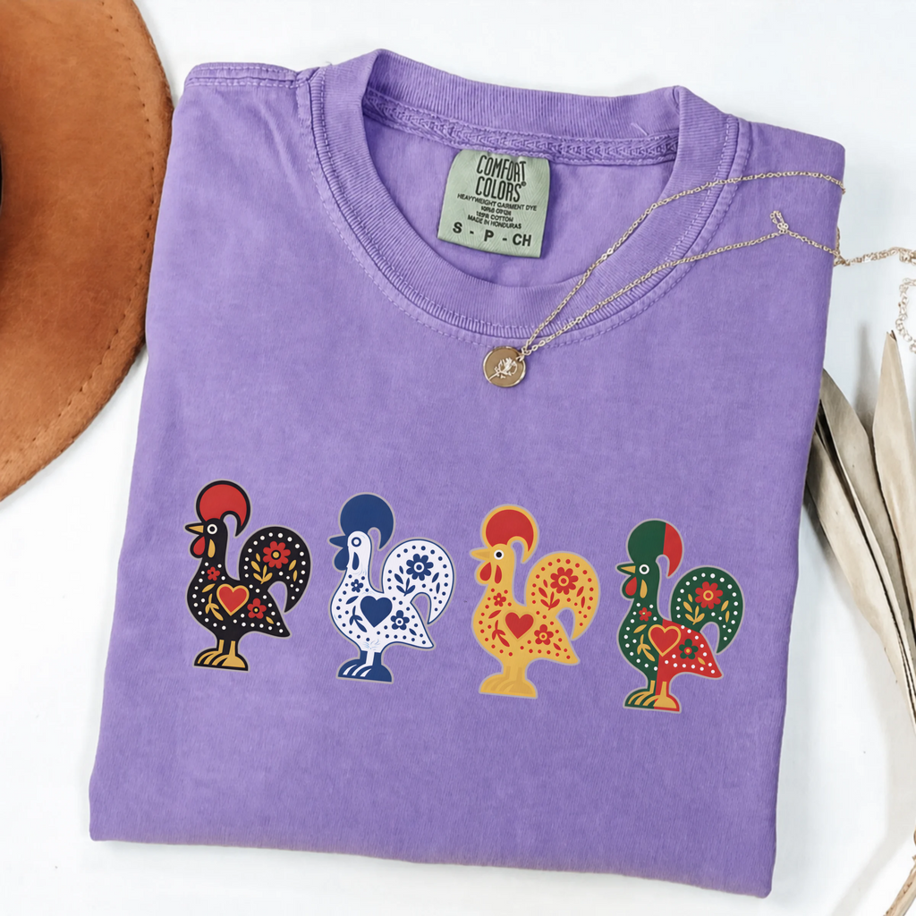 Violet garment-dyed T-shirt featuring four colorful Portuguese folk-art roosters in a row