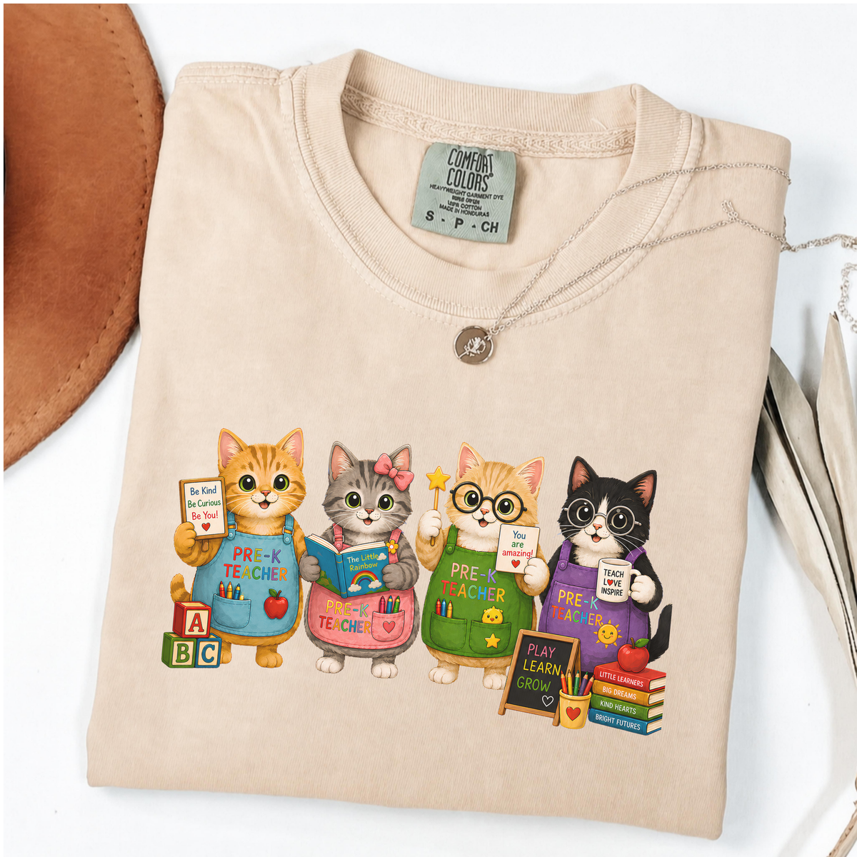Ivory T-shirt with four cartoon cats dressed as colorful pre-K teachers.
